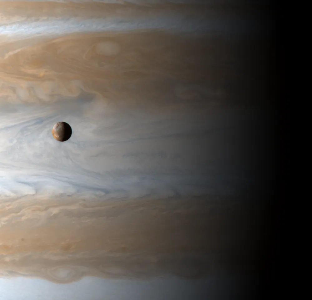 Spacecraft image of a small moon in front of a large planet