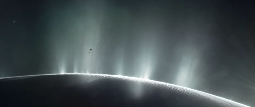 An illustration shows the curving horizon of an icy moon's surface, from which several jets of ice particles and water vapor spray, catching the Sun's light. A robotic spacecraft, Cassini, is visible as a small shape in the distance, headed for the icy plumes.