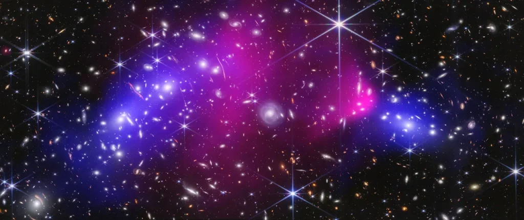 Webb near-infrared data combined with Chandra X-ray data of the Bullet Cluster show many overlapping objects, including foreground stars, galaxies in galaxy clusters, and distorted background galaxies behind the galaxy clusters, set against the black background of space. A large blue oval, two pink areas, and a smaller blue area are layered on top.