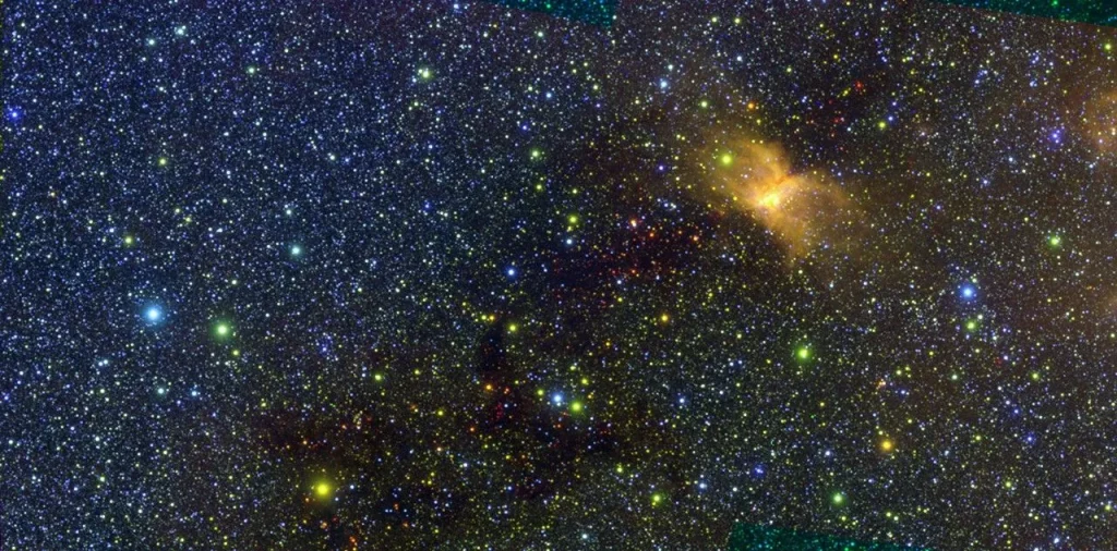 This infrared image of the Vela Molecular Ridge was captured by SPHEREx and is part of the mission’s first ever public data release. The thousands of stars in the image are mostly represented in shades of blue and green. The yellow patch on the right side of the image is a cloud of interstellar gas and dust that glows in some infrared colors due to radiation from nearby stars.