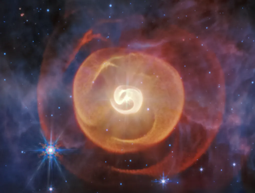 Four dust shells in Wolf-Rayet Apep expand away from three central stars that appear as a single pinpoint of light. The shells are curved, and the interior shell looks like a backward lowercase e shape.