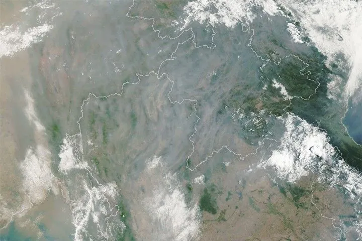 A satellite image shows gray smoke obscuring most of the landscape around Chiang Mai except for small areas where mountain ridges are visible.
