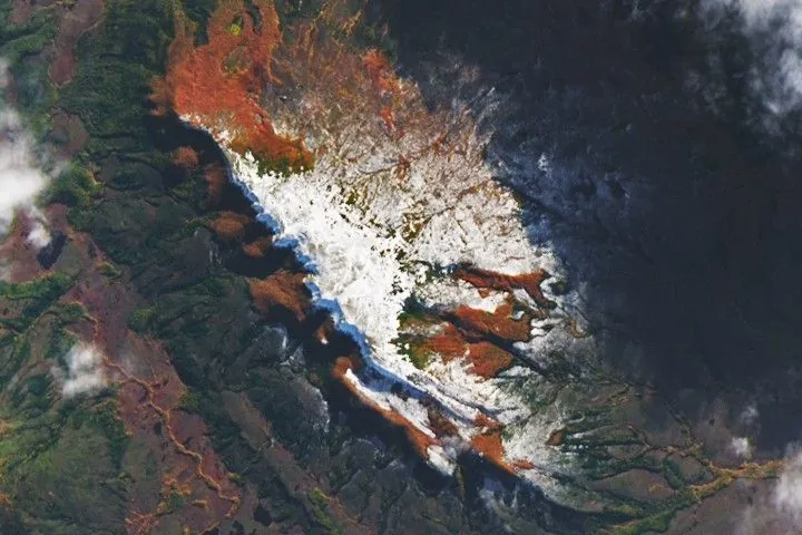 Hills tinged with reddish orange appear through a break in the clouds.