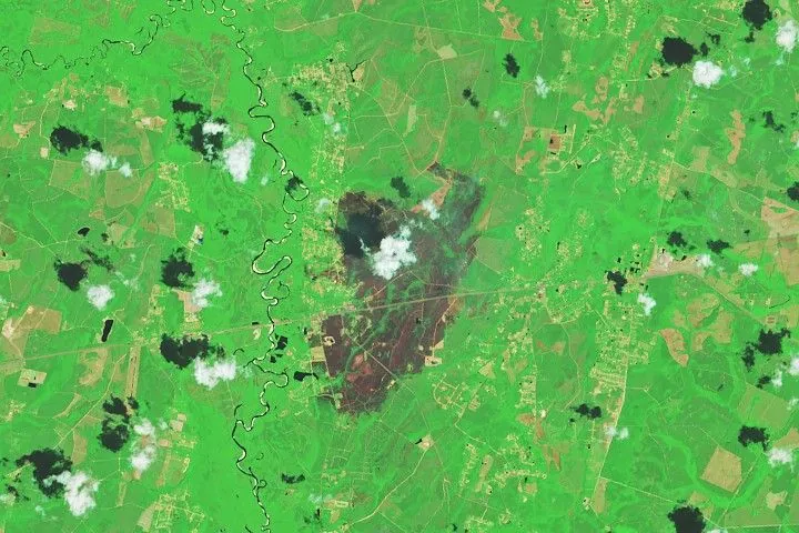 A patch of burned area near Atkinson appears gray amid a background of green. Small scattered clouds are visible in the lower part of the image.