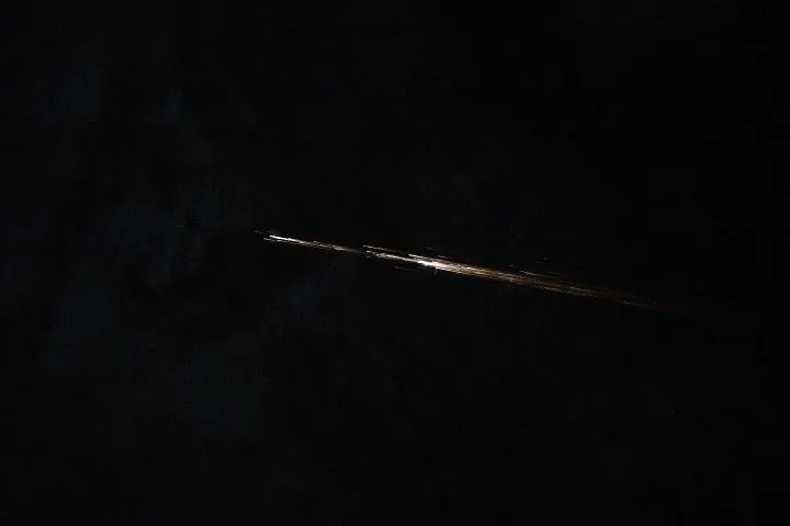 Several long streaks of light are clustered in a line pattern as they streak across a dark background.