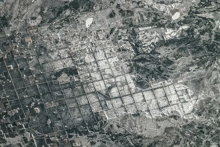 Farm fields and roads are laid out in a repeating rectangular pattern in this snowy image.