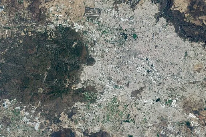 Images of Guadalajara in 1986 (left) and 2026 (right) shows the city expanding westward into an area that had been mostly farmland. Guadalajara Stadium appears as a small circular feature on the left side of the 2026 image.