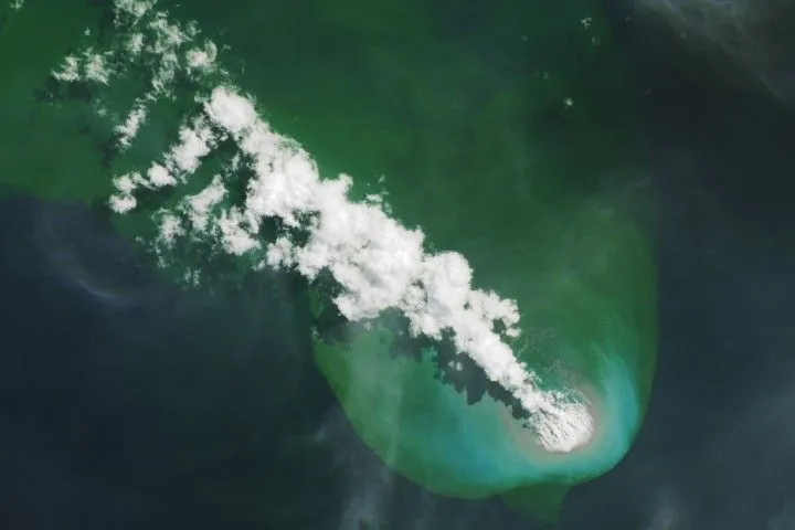 A bright-white volcanic plume and an area of greenish water extend to the northwest from an underwater eruption.