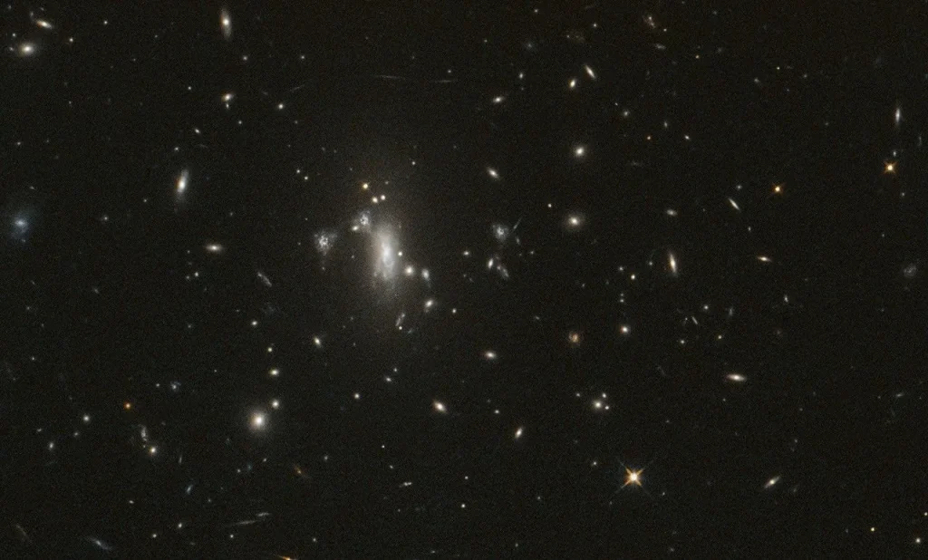 Several galaxies shine against black space, with a large cluster near center-left.